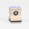 A small rectangular wooden rubber stamp with a clear top, a black circular logo with a white "P" on the front, and the words "SNAIL MAIL" printed in blue on the top.