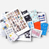 An assortment of illustrated stamp booklets and sheets in a box, featuring multiple colorful designs, grid layouts, and legible text such as "STAMP OUT HATE" and "ARTIST SERIES".