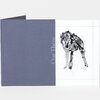 An open folded card or booklet with a slate-blue cover printed vertically with the words "Out There" and a white interior page featuring a black-and-gray abstract animal-like illustration and dotted border lines.