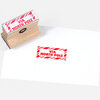 A wooden rubber stamp with a clear top label reading "VIA NORTH POLE" and a red stamped impression of the same text inside a striped border.