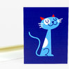 A greeting card featuring a stylized blue cat with red ears, a white belly, and a dark blue background.