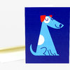 A folded greeting card with a dark blue front featuring a stylized light blue dog with red ears and simple line-drawn facial features.