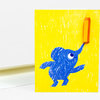 A bright yellow greeting card shows a blue cartoon elephant balancing a pencil on its trunk.