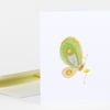 A folded white greeting card featuring a colorful stylized green butterfly and a small yellow flower illustration on the front.