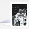 A folded greeting card featuring a black-and-white illustration of three horse heads, braided strands, and circular moon phases with no clearly legible text.