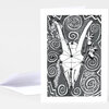 A folded greeting card with a black-and-white illustration of a goat skull surrounded by spiral patterns, with a blank matching envelope behind it.