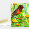 A folded greeting card featuring a colorful illustration of a brown bird standing among orange mushrooms and small flowers in a green field.