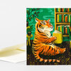 A greeting card shows an orange tiger sitting and reading a yellow book beside bookshelves and potted plants.