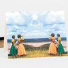 A folded greeting card showing four women in colorful dresses looking out over a coastal landscape, with two holding binoculars.