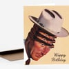 A folded greeting card shows an illustrated cowboy-style face with a white hat and the words "Happy Birthday" in script.