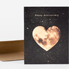 A greeting card with the text "Happy Anniversary" above a heart-shaped moon illustration on a black starry background.