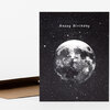 A black greeting card with a starry background, the words “Happy Birthday” near the top, and a large disco ball pictured like a moon in the center.