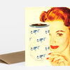 A greeting card featuring a vintage-style illustration of a woman holding a blue-and-white floral mug filled with coffee, with a brown envelope behind it.