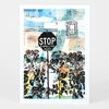 A postcard featuring a collage-style illustration of a black stop sign that reads "STOP 2 SMELL THE ROSES" above rose stems and mixed blue, white, and pastel architectural shapes.