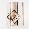 A cream-colored fabric wrap with vertical orange and black stripes and a central butterfly-and-flower graphic, with small text reading "VICTORY GARDEN OF TOMORROW" near the bottom.