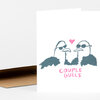 A folded white greeting card shows an illustration of two gulls wearing sunglasses with a pink heart above them and the pink text "COUPLE GULLS" below.