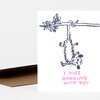 A white greeting card with a sketch of a hanging animal and the pink text "I MISS HANGING WITH YOU" on the front.