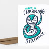 A folded birthday card with the text "HAVE A CHARMING BIRTHDAY" and a stylized teal-and-black illustrated cobra on the front.