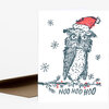 A folded greeting card with a stylized owl wearing a red Santa hat, small snowflakes, and the text "HOO HOO HOO" on the front.