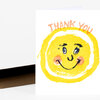 A folded greeting card with a hand-drawn yellow smiling sun face and the words "THANK YOU" across the top in peach lettering.