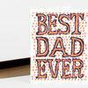 A folded greeting card with large hand-drawn block letters reading “BEST DAD EVER” in orange and dark navy, surrounded by small orange starburst marks.