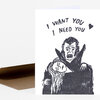 A folded card or booklet with a black-and-white illustration of a vampire holding a woman and the text "I WANT YOU I NEED YOU" with a small heart.