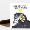 A folded greeting card with the text "YOU GET MY GEARS GOING," a yellow heart, and a black-and-yellow monkey head illustration on the front.