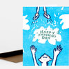 A folded greeting card with a bright blue illustrated cover showing a person reaching up and the text "HAPPY FATHER'S DAY" in the center.