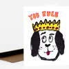 A folded greeting card with the words “YOU RULE” and a cartoon dog wearing a yellow crown with pink and black details.