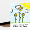 A folded greeting card with a hand-drawn scene of three yellow flowers, clouds, a bright sun, and the text "MOM, THANKS FOR HELPING US GROW."