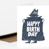 A folded greeting card with a black-and-white illustration of a figure in a coat and hat holding a sign that reads "HAPPY BIRTH DAY".