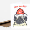 A folded greeting card shows a pug wearing a red Santa hat with the text "BAH HUM PUG" above it.