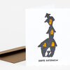 A folded greeting card shows a tall spooky house illustration with glowing yellow windows, a black cat at the bottom, and the text "HAPPY HALLOWEEN" on the front.