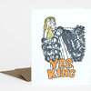 A folded greeting card with a stylized illustration of a blonde figure in a black outfit and the words "YES KING" in orange block letters on the front, shown with a kraft paper envelope.