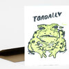 A white folded greeting card or note card printed with a large green-and-black toad illustration and the word "TOADALLY" at the top.