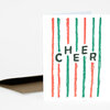 A folded greeting card with a white front printed with vertical red and green brushstroke stripes and the word "CHEER" in dark letters, shown with a brown envelope.