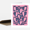 A folded greeting card shows a pink square design filled with dark heart shapes and the word "MOM" repeated three times.