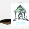 A folded greeting card with a dog illustration under a green roof and the text "CONGRATS ON THE NEW HOUSE" in light blue on the front.