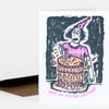 A folded birthday card featuring a hand-drawn person in a pink party hat and shirt holding a knife in a decorated cake, with the text "HAVE AN INSANE BIRTHDAY" on the front.