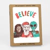 A kraft cardboard box set for six letterpress printed cards with kraft envelopes, featuring the word "BELIEVE" above an illustration of Santa, a bigfoot-like figure, and an alien.