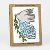 A kraft-paper box set with a front window showing a dove illustration holding an olive branch and the word "PEACE" in large blue letters, with "SIX LETTERPRESS PRINTED CARDS" and "w/ KRAFT ENVELOPES" printed on the box.
