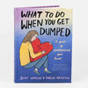 A hardcover book titled "WHAT TO DO WHEN YOU GET DUMPED" with an illustration of a person holding a broken red heart on the cover and the subtitle "a guide to unbreaking your heart."